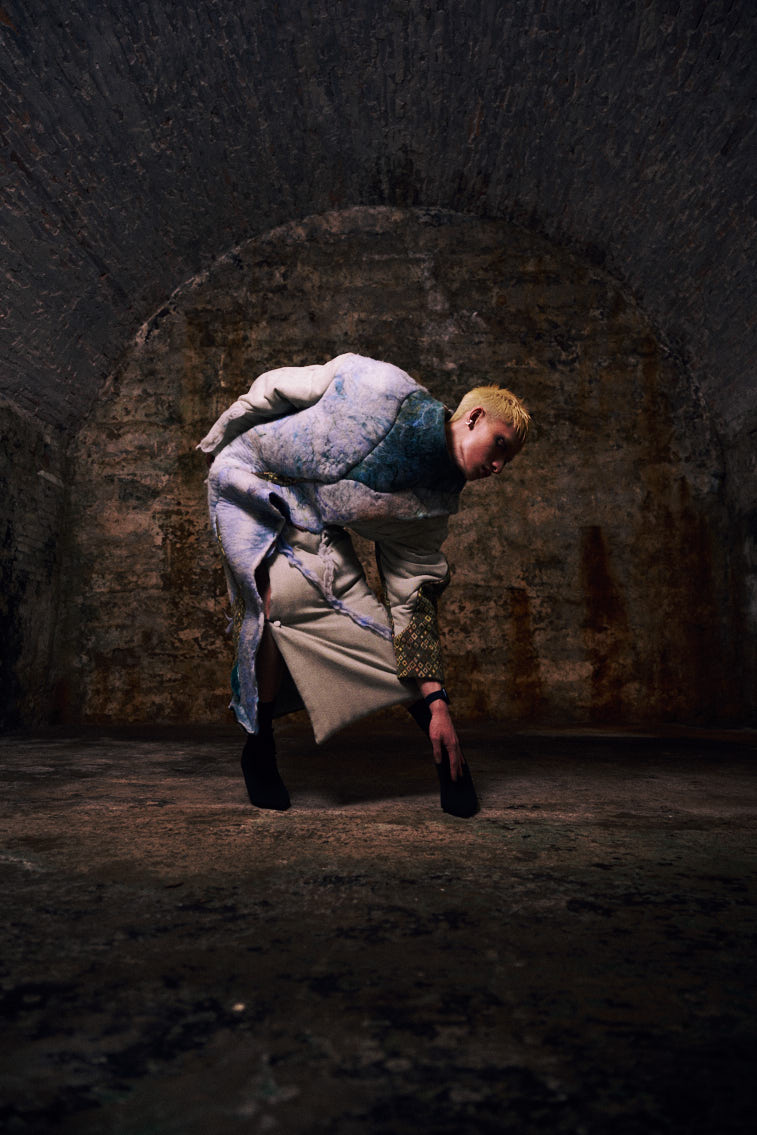 a man wear a blue tone color wool felting cloth in historic place, in tunnel