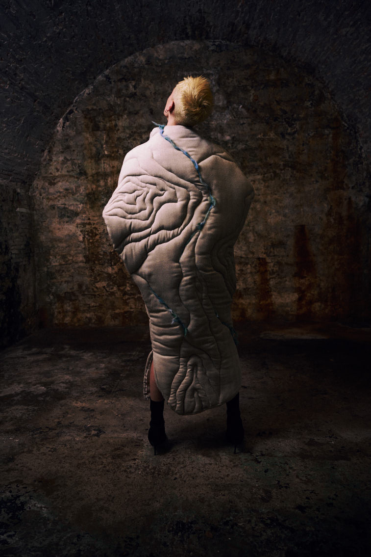 a man wear a blue tone color wool felting cloth in historic place, in tunnel
