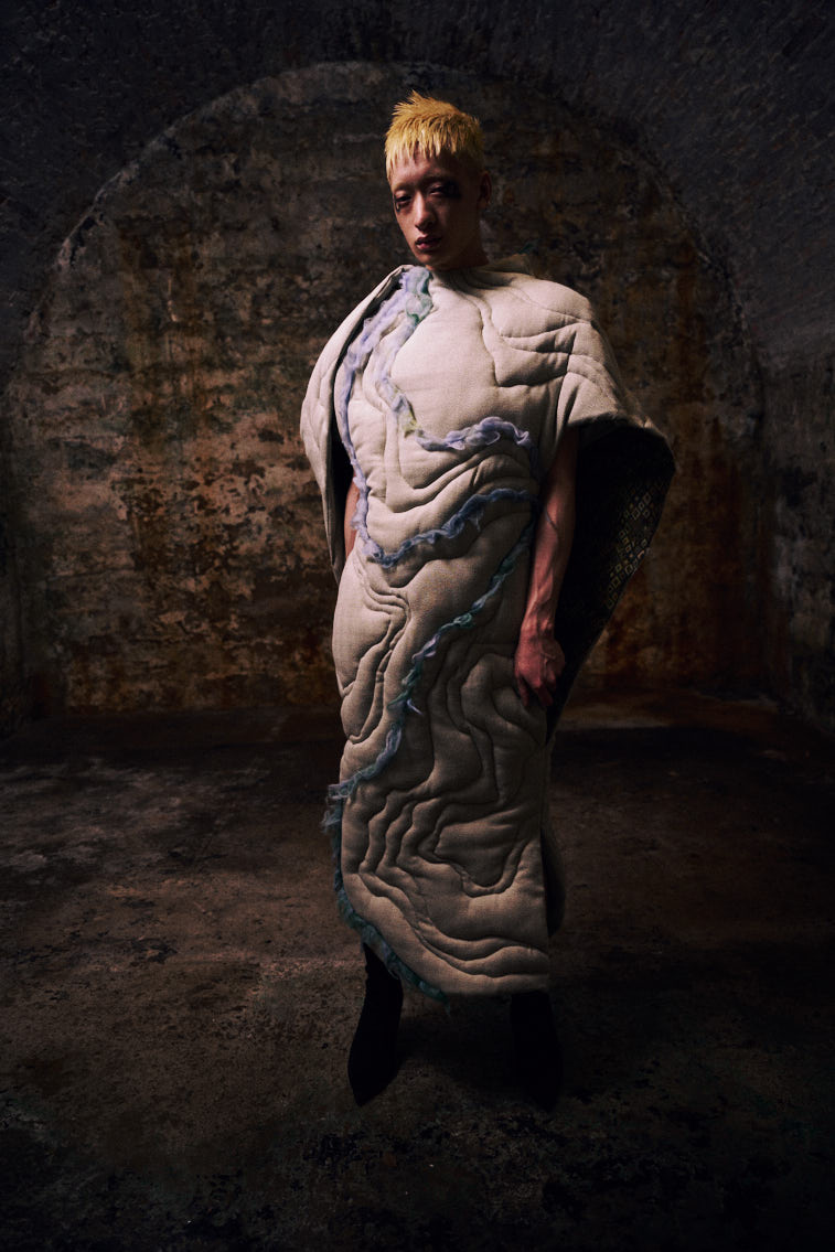 a man wear a blue tone color wool felting cloth in historic place, in tunnel