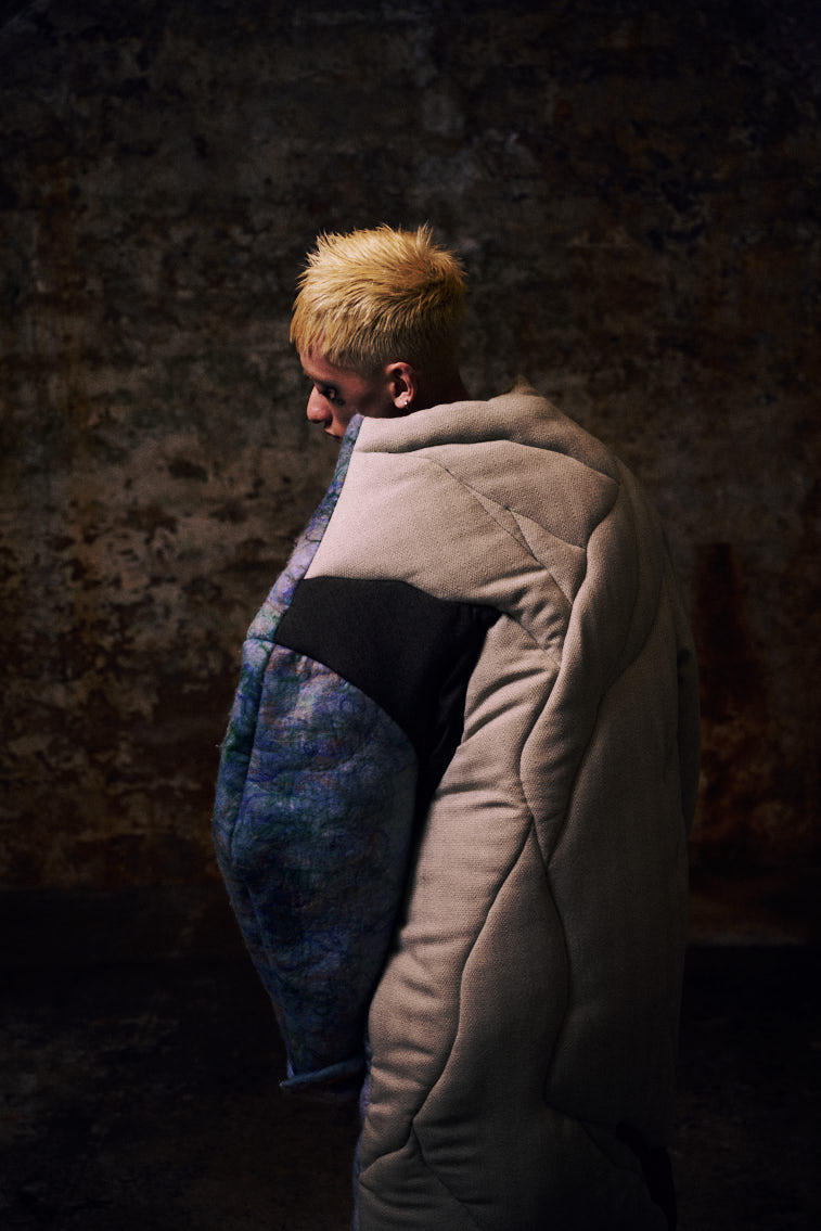 a man wear a blue tone color wool felting cloth in historic place, in tunnel